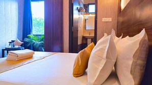 Une chambre d’hôtel avec un lit, une table de chevet, une fenêtre avec des rideaux, un lavabo et un miroir.