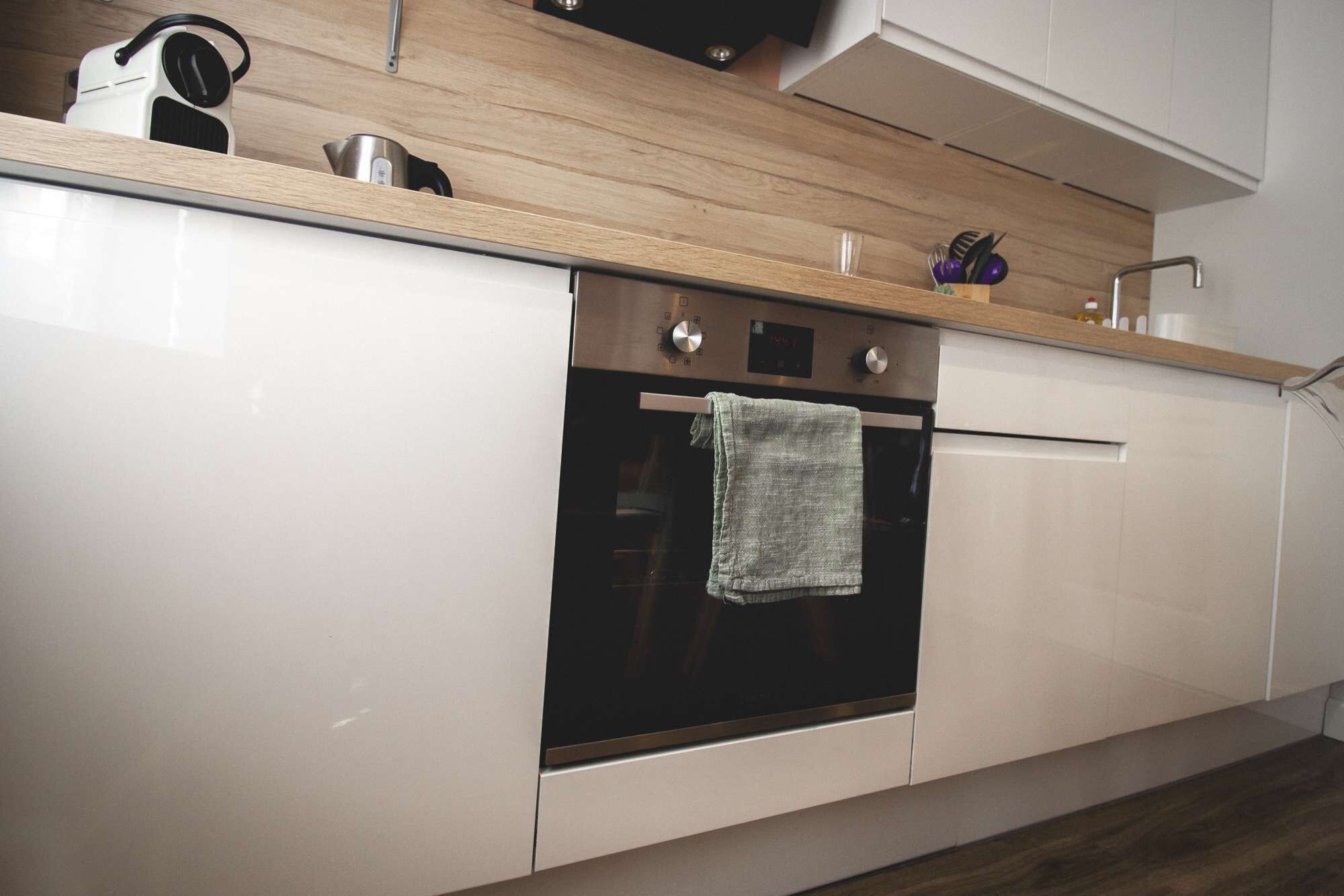 Une cuisine moderne dotée d’un four encastré, d’une bouilloire et d’un plan de travail en bois.