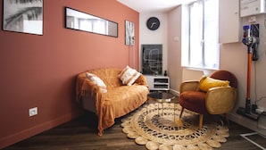 A cozy living room with a sofa, a chair, a round coffee table, and a large woven rug. - ♥♥ La Cachette Rouge ♥♥ (saint valery sur somme)
