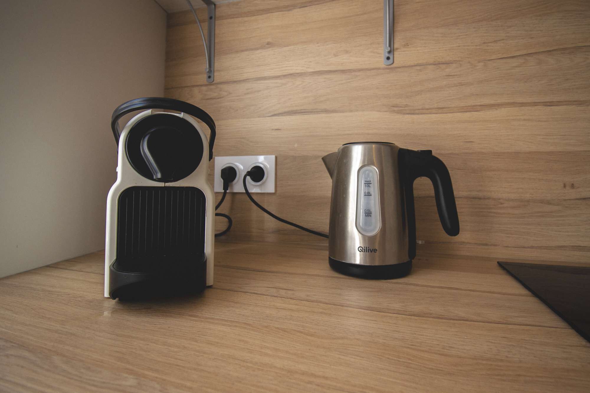 A kitchen with a kettle and a coffee maker on a wooden countertop.