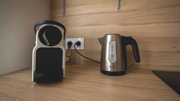 A kitchen with a kettle and a coffee maker on a wooden countertop.