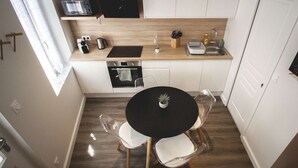 A compact kitchen with a black round table, two chairs, and a small potted plant. - ♥♥ La Cachette Rouge ♥♥ (saint valery sur somme)