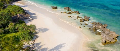 På stranden, hvit sand, solsenger og parasoller