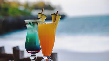 Two cocktails on a table with a blurred beach and ocean in the background.