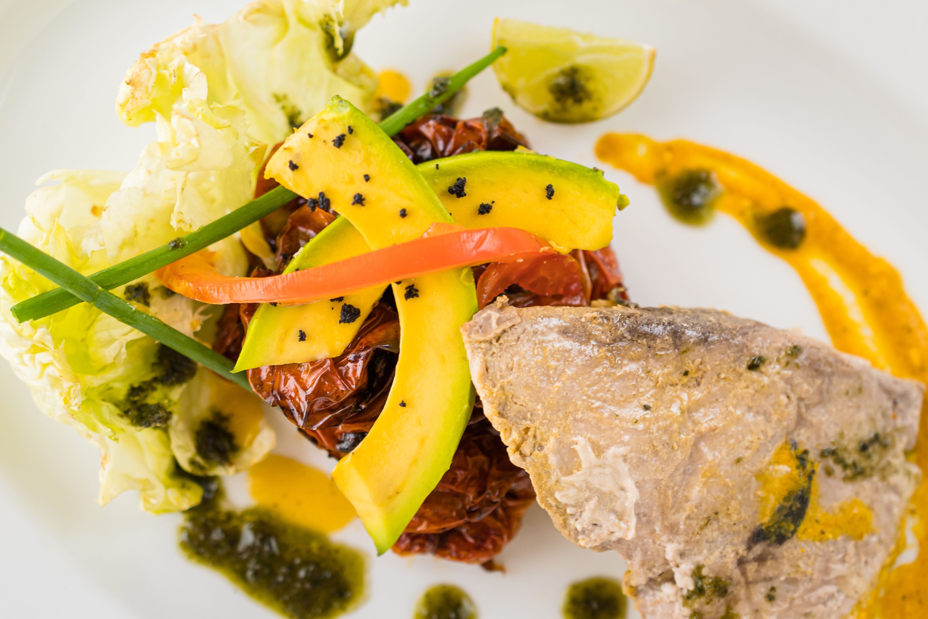 Un plato con varios vegetales y un trozo de carne, posiblemente pollo, sobre una vajilla blanca.