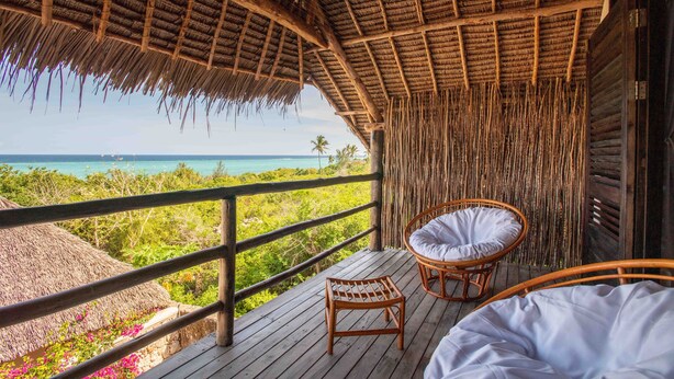 A wooden deck with a thatched roof, wicker chairs, and a bed. - Sunshine Bay Zanzibar - Adult Only (Matemwe)