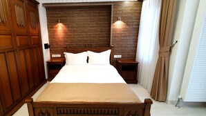 Een slaapkamer met een groot bed, een houten garderobe, twee nachtkastjes en een hoofdbord met ingebouwde verlichting.