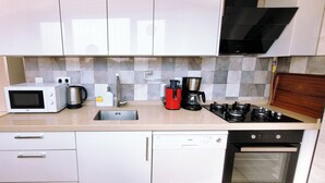 Een moderne keuken met witte kasten, een magnetron, een koffiezetapparaat, een gasfornuis en een vaatwasser.