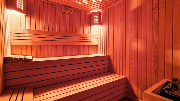 Een sauna met houten banken en een bank met rugleuning.
