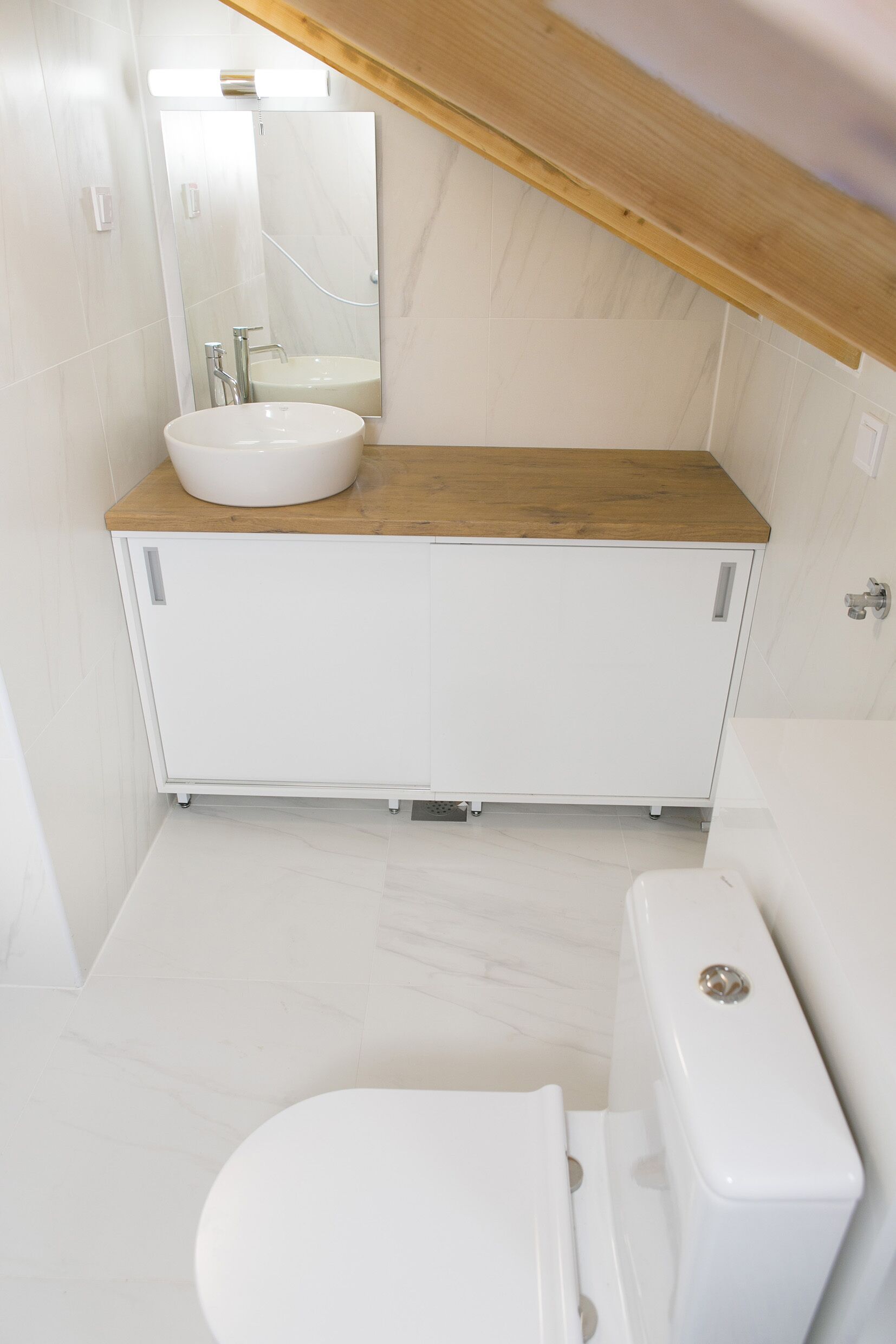 A modern bathroom with a white sink, wooden countertop, and a toilet.