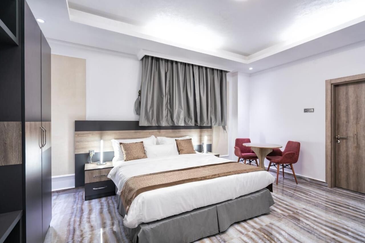 Una habitación de hotel moderna con una cama grande, mesitas de noche, un escritorio con sillas y un armario.