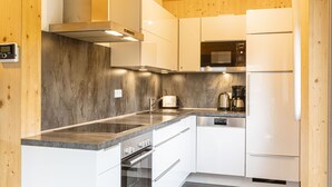 A modern kitchen with white cabinets, a stainless steel range hood, a built-in microwave, and a dishwasher.