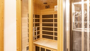 A sauna with a wooden interior, a control panel, and a glass door leading to a shower area.