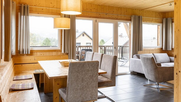 A wooden interior with a dining table, benches, and a sofa.