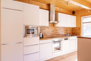 Una cocina moderna con armarios blancos, electrodomésticos de acero inoxidable y detalles de madera.