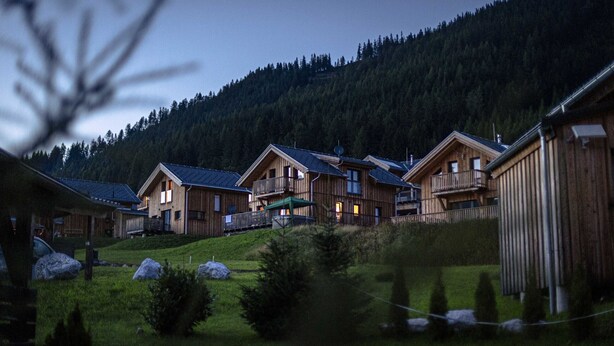 A row of wooden cabins with balconies, set against a backdrop of a forested hillside. - Superior Chalet # 61 with IR-Sauna (Hohentauern)