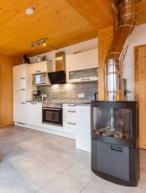 Una cocina moderna con armarios blancos, electrodomésticos de acero inoxidable y una estufa a leña.