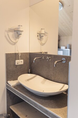 A modern bathroom with a white sink, a mirror, and a towel rack.