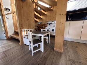 Una cocina compacta con vigas de madera, una mesa de comedor, sillas y un microondas.