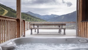 Un pontile in legno con una vasca idromassaggio e una panca, con vista su un paesaggio montuoso.