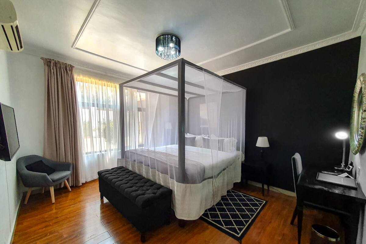 Une chambre à coucher avec un lit à baldaquin, un banc, un bureau et une chaise.