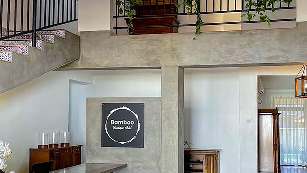 A spacious hotel lobby with a high ceiling, a staircase, a reception desk, and a sign reading "Bamboo Boutique Hotel". - Bamboo Boutique (Lilongwe)