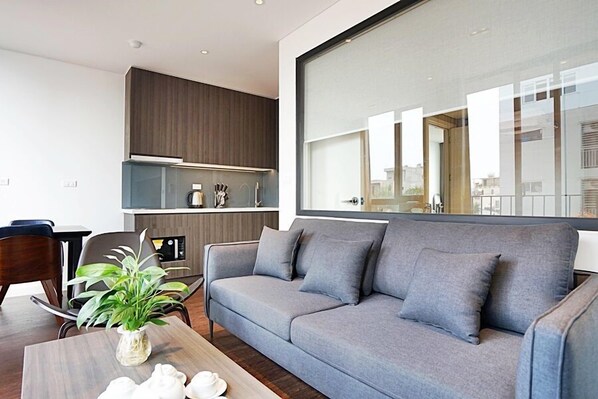 A modern living room with a grey sofa, a wooden coffee table, and a plant.