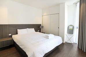 A hotel room with a large bed, a bedside table, a nightstand, a wardrobe, and a window with curtains. - Hanoi Home 3 - Luxury Apartment (Hanoi)