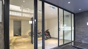 En moderne bygningseingang med glasdøre, en motorcykel indeni og en trappe, der fører op til et andet plan.