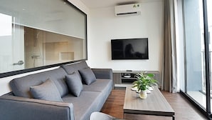 En moderne stue med en grå sofa, et fladskærms-tv og et træsofabord med planter.