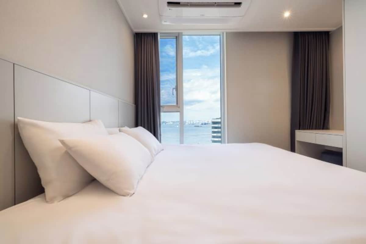 Una habitación de hotel moderna con una cama grande, vistas al agua y un balcón.