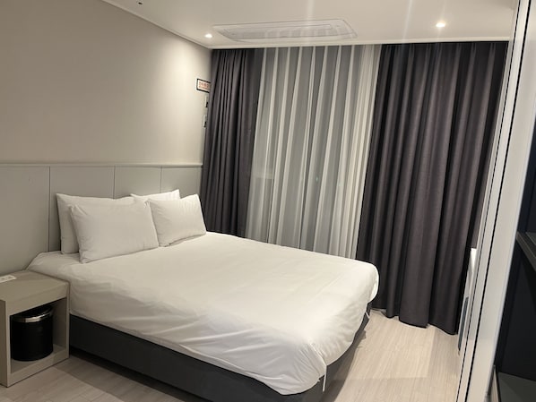A modern hotel room with a large bed, a bedside table, and a window with curtains. - Ocean Park 9 (Incheon)