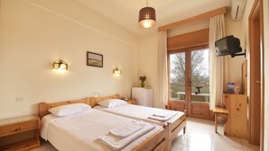 Una habitación de hotel con dos camas de madera, un escritorio pequeño, un televisor montado en la pared y una ventana con cortinas.