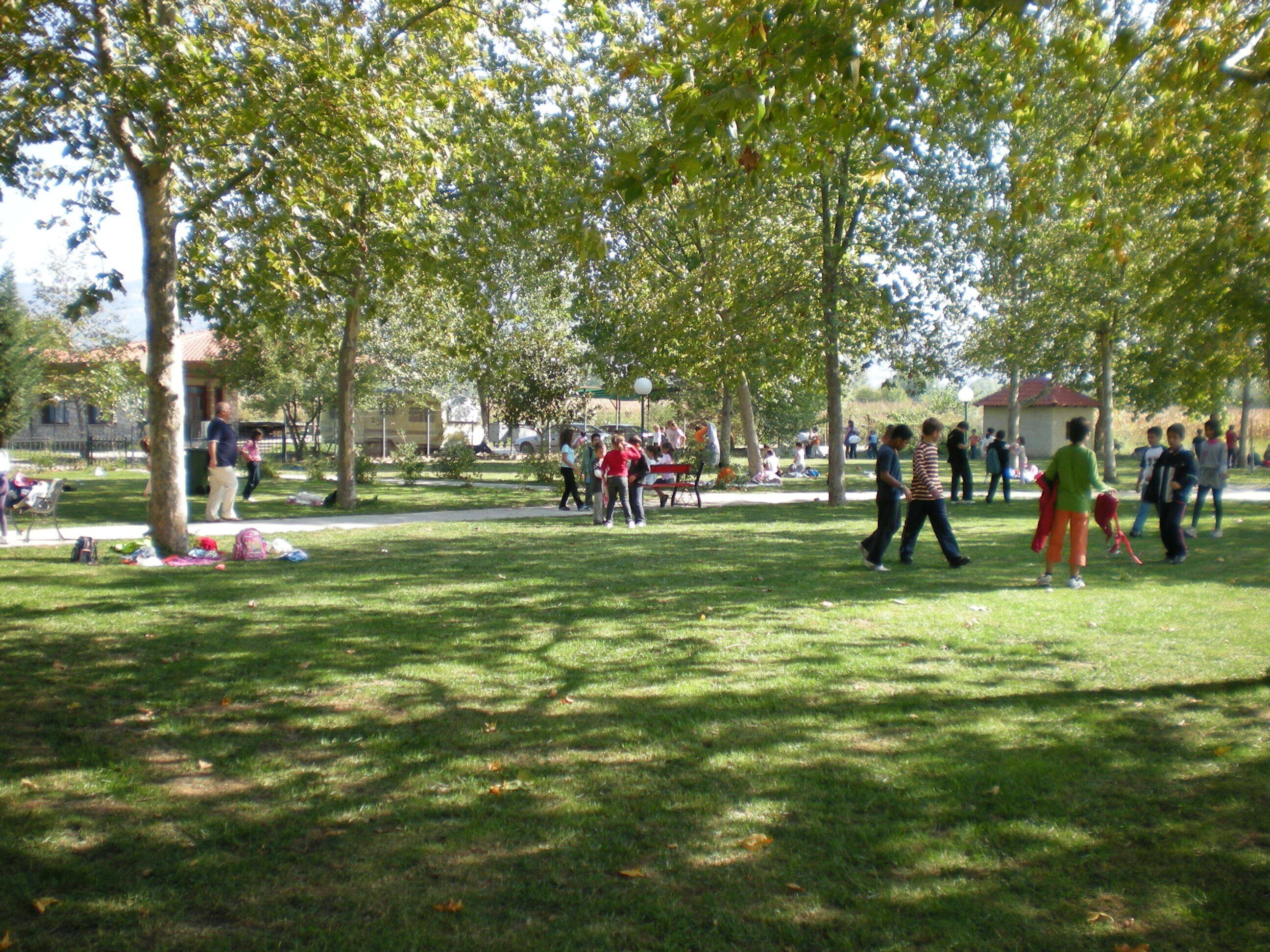 A park with people walking and sitting on the grass.