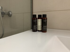Three bottles of Olive Era body wash on a white bathroom counter. - Rodos Town Luxury Apartment (Rhodes)