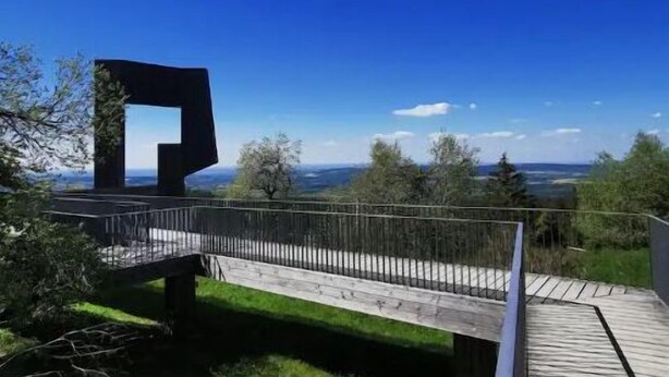 A wooden deck with a metal railing overlooking a scenic landscape.