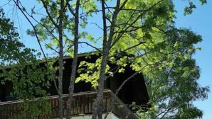 A two-story building with a balcony, surrounded by trees and a well-maintained lawn.