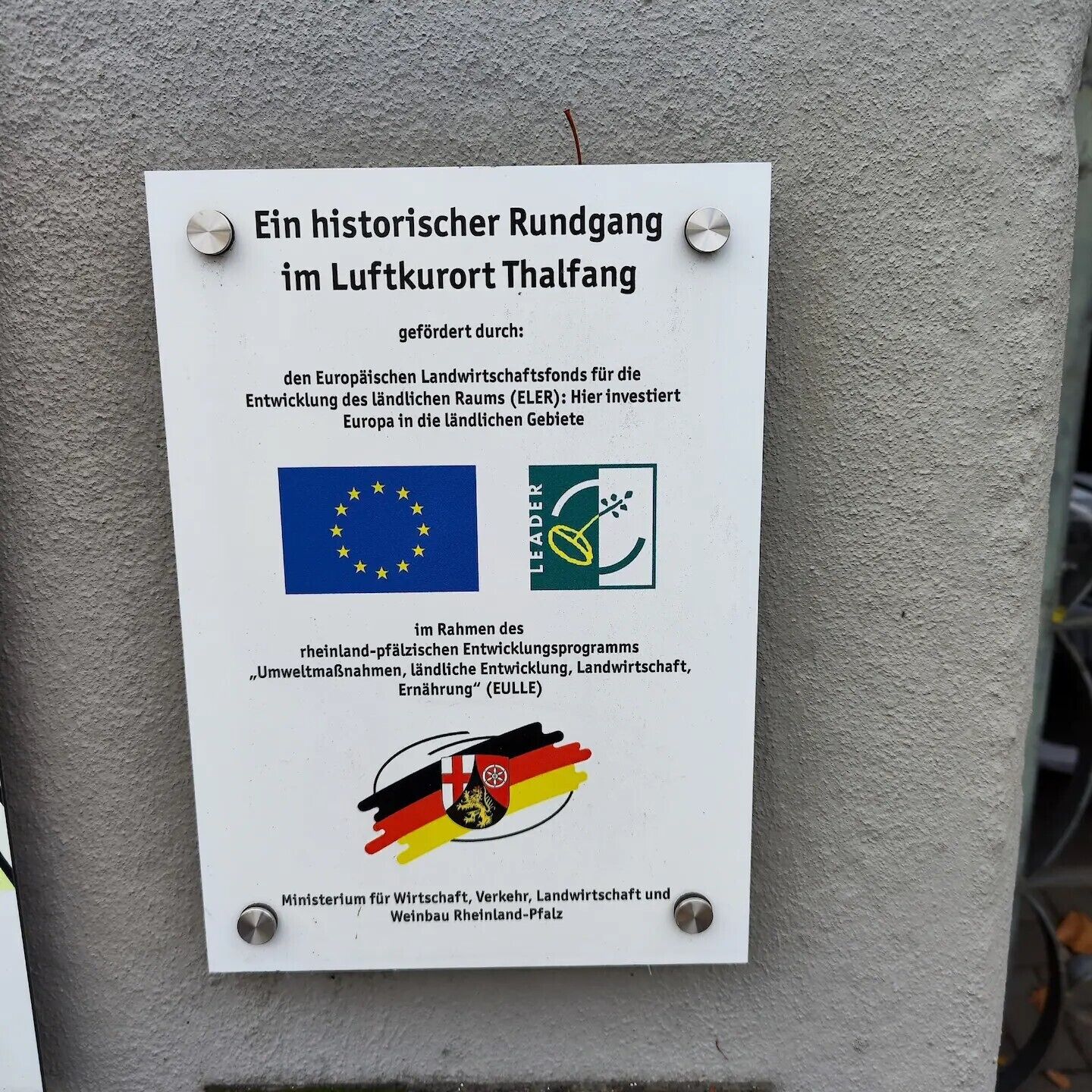 Ein an der Wand befestigtes Schild mit Text auf Deutsch.