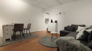 A compact living space with a kitchenette, a dining area, and a seating area with a sofa and a small round table.