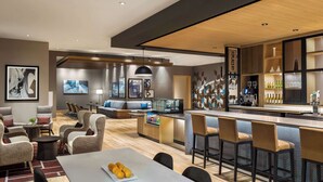 Un moderno vestíbulo de hotel con zona de bar, asientos y obras de arte.