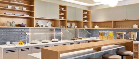 A modern kitchen with a central island, bar stools, and built-in shelves.