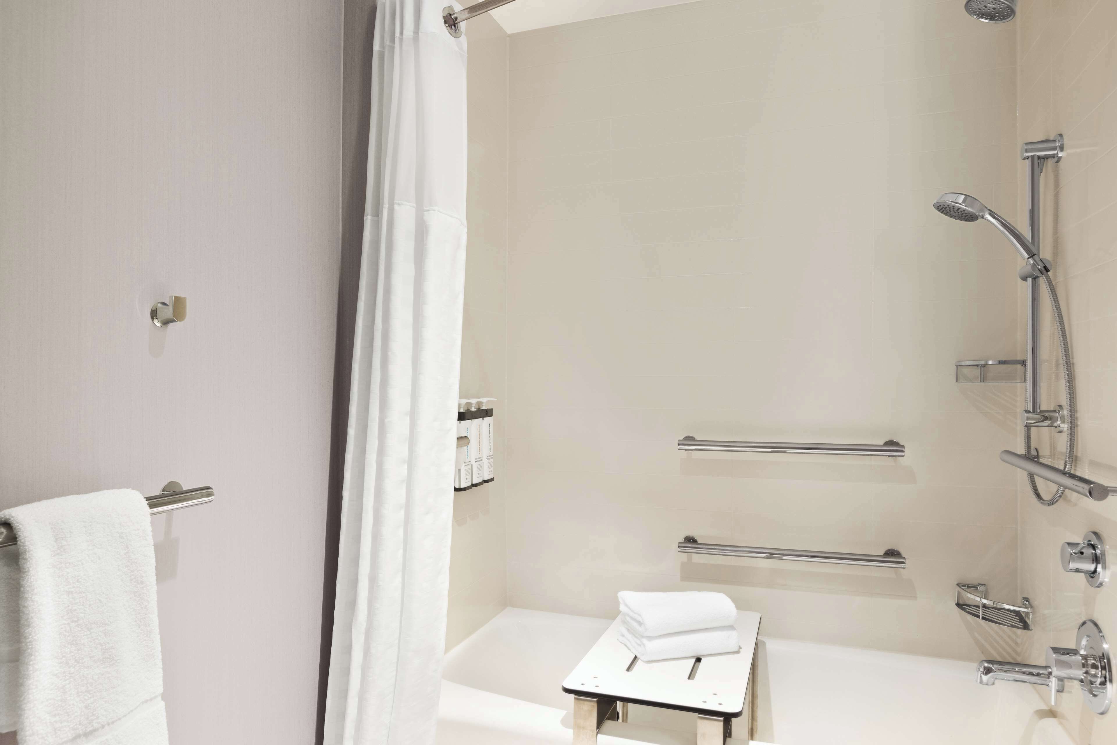 A modern bathroom with a shower, a bathtub, and a small table with towels.