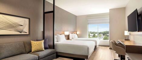 Una habitación de hotel moderna con sofá, dos camas, escritorio y televisor.