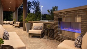 Un espacio al aire libre con patio, asientos, una chimenea y un muro de ladrillo.