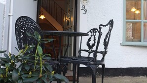 A black metal chair and table outside a building with a white exterior and a window with a view. - Bashall Barn, Eaves Hall, Outbarn all Close by (Clitheroe)