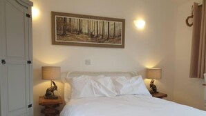 A bedroom with a bed, two bedside lamps, a painting above the bed, and a wardrobe to the left. - Bashall Barn, Eaves Hall, Outbarn all Close by (Clitheroe)