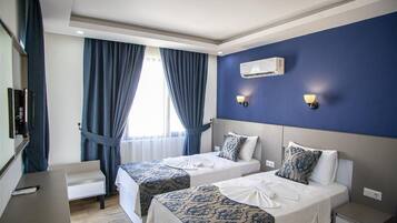 Habitación de hotel con dos camas, un escritorio, un televisor y un equipo de aire acondicionado.