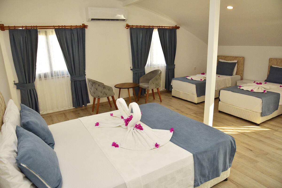 A hotel room with two beds, a chair, and a small table.