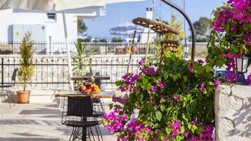 An outdoor seating area with tables and chairs, surrounded by potted plants and flowers.