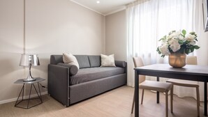 Ein modernes Wohnzimmer mit grauem Sofa, einem kleinen Tisch und einem Blumenstrauß.